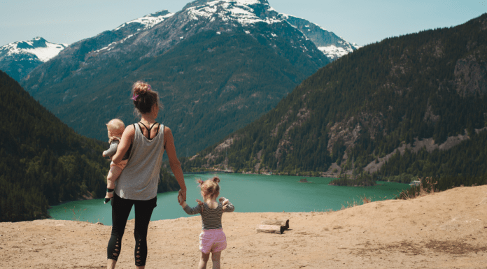 a mom with her two children looking at a beautiful lake between the mountains.